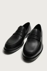 Mocasín de vestir para hombre, confeccionado en cuero marrón con diseño clásico de antifaz en el empeine, horma redonda y suela con ligero tacón.