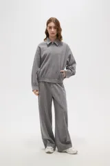 Campera de estilo deportivo en color gris, con cuello solapa, cierre frontal completo y mangas largas con puños ajustados. Presenta un diseño holgado con cintura elástica.