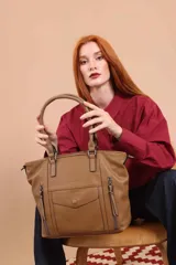 Cartera tipo tote de diseño estructurado en símil cuero, con doble asa rígida y correa regulable. Presenta múltiples bolsillos frontales con cierre y solapa, ofreciendo un estilo versátil y espacioso.