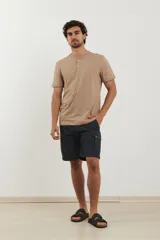 Remera tipo henley de manga corta, color beige, con cuello redondo y cartera de botones frontal.