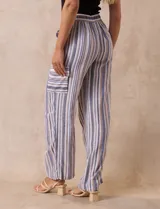Pantalón de lino con rayas verticales en tonos beige, azul y gris. Tiene pretina elastizada, bolsillos inclinados en la parte delantera y un bolsillo tipo cargo en el lateral. Marca Zac & Rachel.