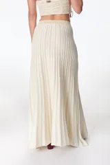 Falda larga color crema con lurex dorado, de tejido de punto acanalado y corte recto con abertura lateral.