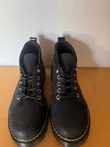 Borcego negro de cuero con cordones, suela track y detalle de costuras amarillas.