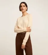 Suéter de punto color marrón chocolate, con cuello redondo y mangas largas con puños acanalados. Presenta un diseño básico y versátil de corte recto.