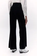 Pantalón de terciopelo negro, de tiro alto y corte acampanado.