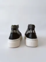 Zapatillas deportivas de caña alta con estampado de piel de reptil en tonos verde y negro, detalles en blanco y suela gruesa blanca.
