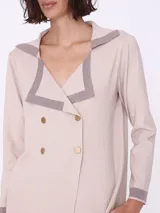 Cárdigan color beige con cuello marinero con borde gris, doble botonadura dorada y mangas largas. Tejido de punto.