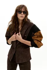 Chaqueta de gamuza con diseño de paneles en colores marrón, chocolate y negro. Presenta hombros estructurados, corte entallado en la cintura y botones forrados al tono.