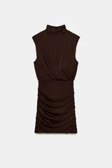 Vestido corto de cuello subido y diseño sin mangas, con cuerpo superior cruzado y falda con detalle de frunces laterales. Cuenta con forro interior y cierre lateral con cremallera oculta.
