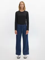 Pantalón jean de pierna ancha, color azul oscuro, con pinzas y detalles de tachas en los bajos. Presenta bolsillos laterales y traseros tipo sastrero.