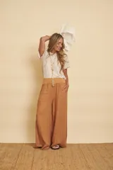 Pantalón de lino tostado, de corte amplio y evasé, con cintura estilo puño y bolsillos laterales.