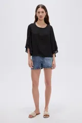 Blusa negra de poliéster, con cuello redondo, mangas 3/4 con volados en capas y diseño holgado.