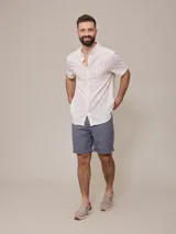 Camisa de manga corta para hombre, color blanco con rayas verticales finas en relieve. Tiene cuello abotonado, bolsillo en el pecho izquierdo y logo bordado pequeño.