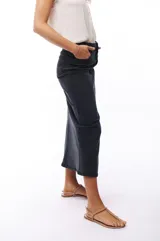 Falda midi de jean color negro, de corte recto y tiro alto, con abertura frontal.