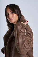 Campera gamulán marrón de símil cuero, con interior de corderoy al tono, cierre frontal con cremallera y cuello con solapas grandes. Presenta detalles de hebillas en los puños y bolsillos laterales con cierre.