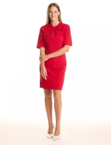 Vestido rojo de crepe, marca Emma & Michele, con cuello a la base y escote entrelazado. Tiene mangas cortas, cierre invisible en la espalda y tajo en el ruedo.