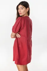 Vestido corto negro de lino italiano, con escote en V, mangas cortas abullonadas y cierre frontal de botones con cintura entallada y tablas.