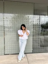 Blusa blanca con escote en V, mangas cortas con volados y lazos en el escote.