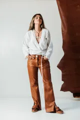 Pantalón de cuero de corte recto y tiro medio, con cierre frontal de botón y cremallera, acabado en tono azul petróleo.