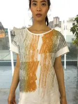 Remera blanca de algodón con estampado abstracto en tonos ocre, verde y gris. De corte holgado y mangas cortas.