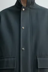 Chaquetón de corte relajado confeccionado en tejido técnico con mezcla de algodón. Presenta cuello solapa, cierre frontal con cremallera oculta por solapa con botones a presión, bolsillos de plastrón con solapa en la cadera y forro interior a contraste.
