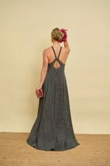 Vestido largo asimétrico color negro con estampado de lunares blancos, escote halter cruzado al frente y diseño con espalda descubierta.