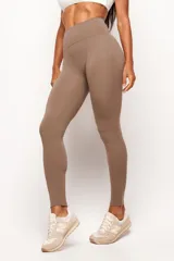 Calza deportiva de tiro alto color tostado, confeccionada en poliamida premium con alta elasticidad. Presenta un diseño sin costura central frontal para mayor comodidad y un recorte curvo en la parte posterior para realce de glúteos.