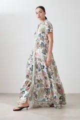 Vestido camisero largo de corte recto, con estampado de arabescos en tonos verde agua, rosa, marrón y gris. Tiene cuello camisero, mangas cortas y cierre frontal con botones.