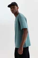 Remera de algodón color verde con cuello redondo ribeteado, mangas cortas y hombros caídos de corte holgado.