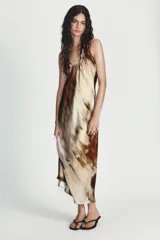 Vestido largo de corte recto con cuello halter y escote redondo, confeccionado en tela satinada con estampado abstracto en tonos tierra y bordó.