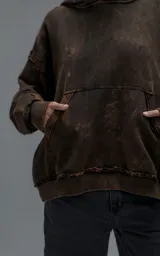 Hoodie de corte oversize y largo crop, confeccionado en algodón con efecto de desgaste y color óxido. Presenta costuras expuestas, detalles de roturas en los bordes y bolsillo frontal tipo canguro.