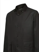 Chaqueta de estilo clásico confeccionada en tela encerada impermeable, con cuello de cotelé, cierre frontal con botones y bolsillos delanteros con solapa.