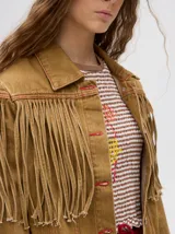 Campera de denim color negro con diseño de flecos en la parte frontal, cuello camisero y cierre frontal con botones metálicos.