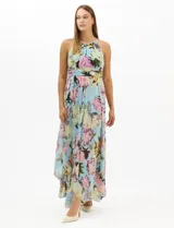 Vestido largo de chifón con estampado floral, cuello halter con pliegues y abertura tipo lágrima. Presenta una cintura drapeada que estiliza la silueta y una falda amplia con capas asimétricas y bajo en picos. Incluye forro interior y cierre invisible en la espalda.