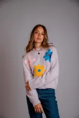 Buzo de punto color fucsia, con cuello redondo, manga larga y bordado de flores en amarillo y azul en el frente.