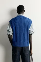 Chaleco de punto trenzado color azul, de corte relaxed fit, con cuello en V y sisas acabadas en rib.