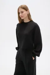 Buzo negro de corte cropped, con cuello redondo y mangas largas abullonadas.