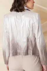 Chaqueta corta de cuero ecológico con diseño degradado de blanco a gris. Tiene cuello tipo solapa, cierre frontal asimétrico con broche y bolsillos con cierre.