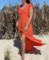 Vestido largo fucsia de lino, con corte recto, breteles anchos con volados y botones frontales. Presenta un tajo lateral.