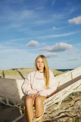 Hoodie rosa claro con estampado gráfico en la espalda en color rojo oscuro. El estampado incluye texto como "GLASSY WAVES SURF COMPANY", ilustraciones de bebidas, frutas, una tabla de surf y palmeras.