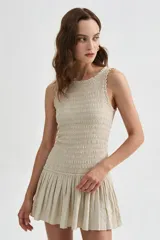 Vestido corto beige sin mangas con cuerpo de nido de abeja elástico y falda corta acampanada con vuelo.