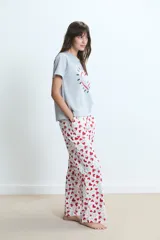 Pijama compuesto por una remera gris de manga corta con estampa frontal de corazón y un pantalón largo blanco con estampado de corazones rojos.