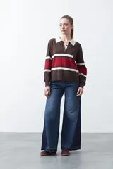 Sweater de tejido de punto con diseño a rayas horizontales en tonos marrón, rojo y crema. Presenta cuello tipo polo con cierre frontal de botones y mangas largas con puños ajustados.