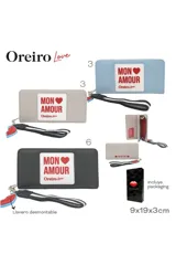 Billetera rectangular de cuero sintético color beige con parche frontal blanco que incluye el texto 'MON AMOUR' y logo de la marca. Cuenta con cierre perimetral y una correa de muñeca desmontable con un dije de labios rojos.