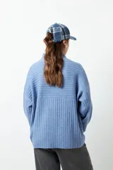 Polera gris de tejido tramado, cuello alto y mangas holgadas.