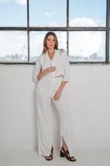 Conjunto de dos piezas color blanco compuesto por un blazer corto de manga 3/4 con cuello solapa y un pantalón de corte wide leg con tajo lateral en el dobladillo.
