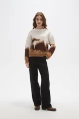 Sweater de punto con diseño de bloques de color en tonos crema, marrón oscuro y caramelo. Presenta una textura afelpada, cuello redondo a la base, mangas largas y corte holgado.