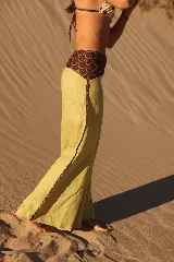 Pantalón de lino de corte ancho y tiro medio, color verde lima. Presenta un caderín y detalles laterales en tela estampada con diseño geométrico en tonos bordó y verde.