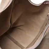 Cartera hobo de cuero color taupe, con diseño slouchy y flecos largos en los laterales. Cuenta con asa para el hombro y herrajes metálicos.