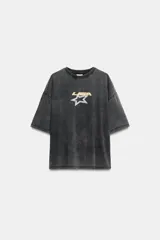 Remera oversize de efecto lavado en color gris oscuro, con cuello redondo, manga corta y estampa frontal de una estrella y el texto 'LISA'.
